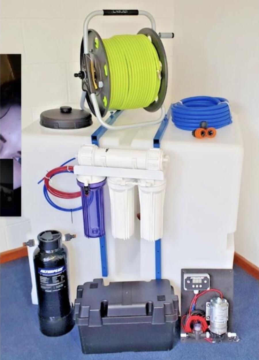 A pure water system: a tank with a hose reel on top, three filter housings and a reverse osmosis membrane below it, a resin vessel and a pump on the floor