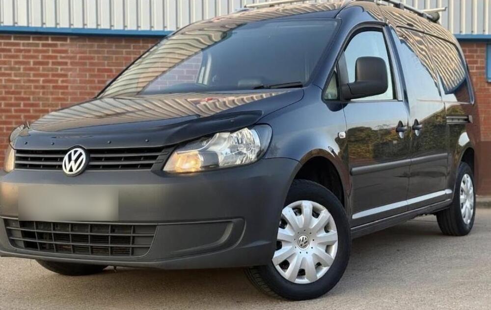 A dark grey Volkswagen Caddy Maxi van with a roof rack carrying a window cleaning pole